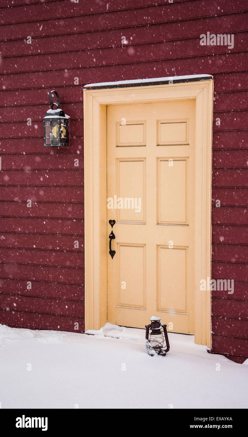 Close up historic red colonial House winter front door, vintage oil lamp, during snow storm Monmouth county, New Jersey, NJ, USA, US, ph image PT Stock Photo