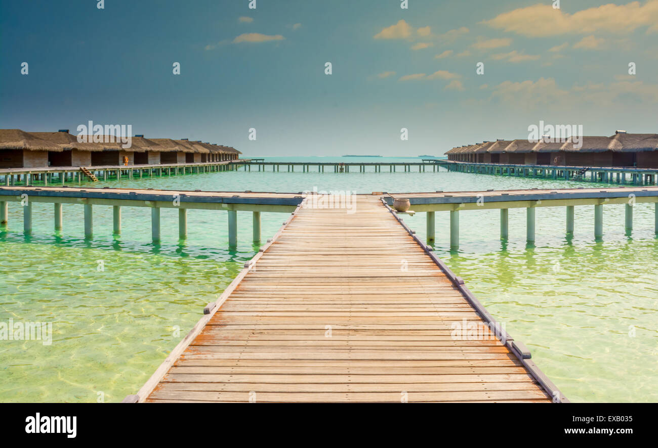 Water bungalows of an island resort extend into the lagoon in Maldives Stock Photo