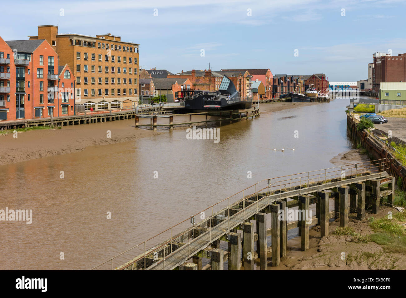 River Hull at low tide with view of Scale Lane swing brige (open), beached obsolete ship, and flanked by buildings. Stock Photo