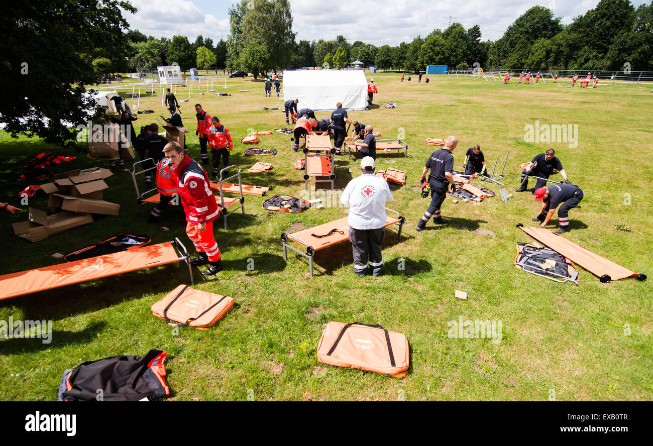 Helpers from the German Red Cross (Deutsches Rotes Kreuz) set up camp beds at a new refugee accommodation centre in Hamburg, Germany, 10 July 2015. The city of Hamburg have been forced to take emergency measures due to the increasing number of incoming refugees. in the Jenfeld district, more than 800 refugees are now supposed to be housed in tents. PHOTO: DANIEL BOCKWOLDT/DPA Stock Photo