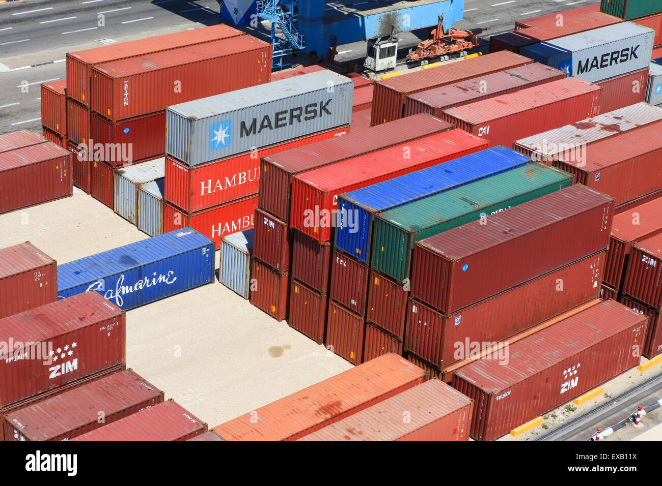 Various brands and colors of shipping containers stacked Stock Photo