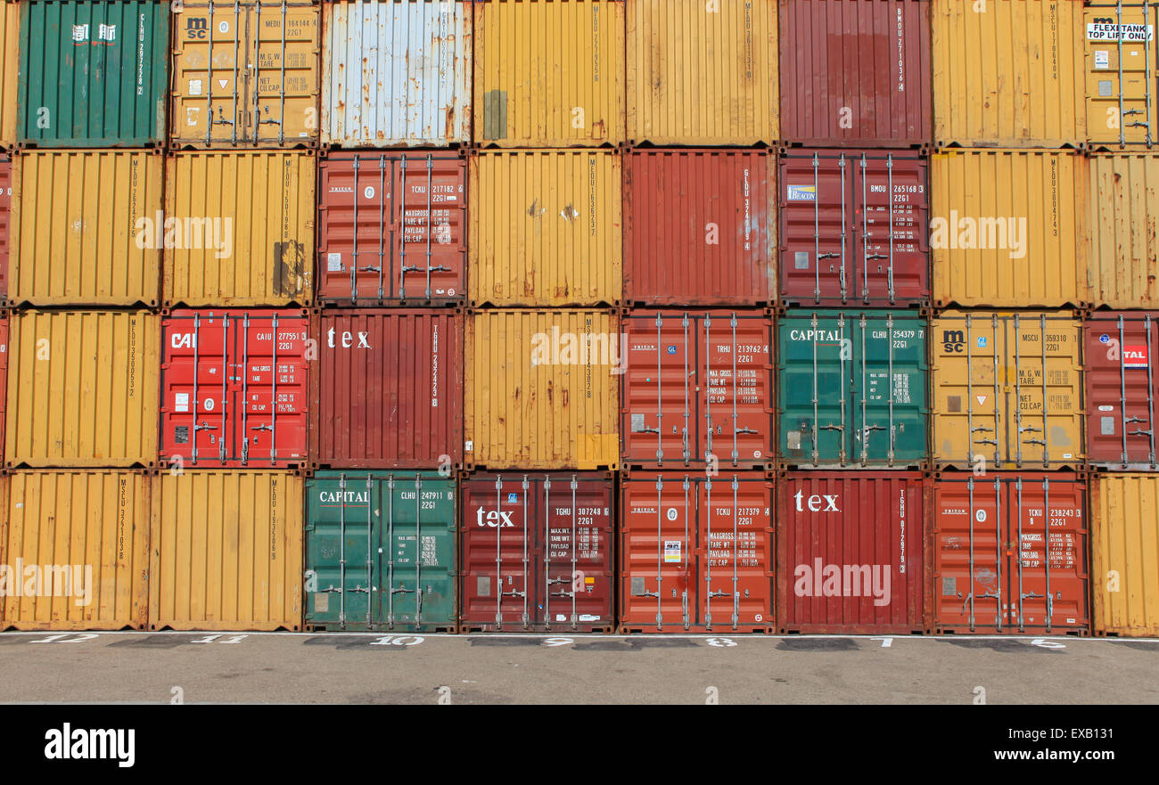 Various brands and colors of shipping containers stacked Stock Photo