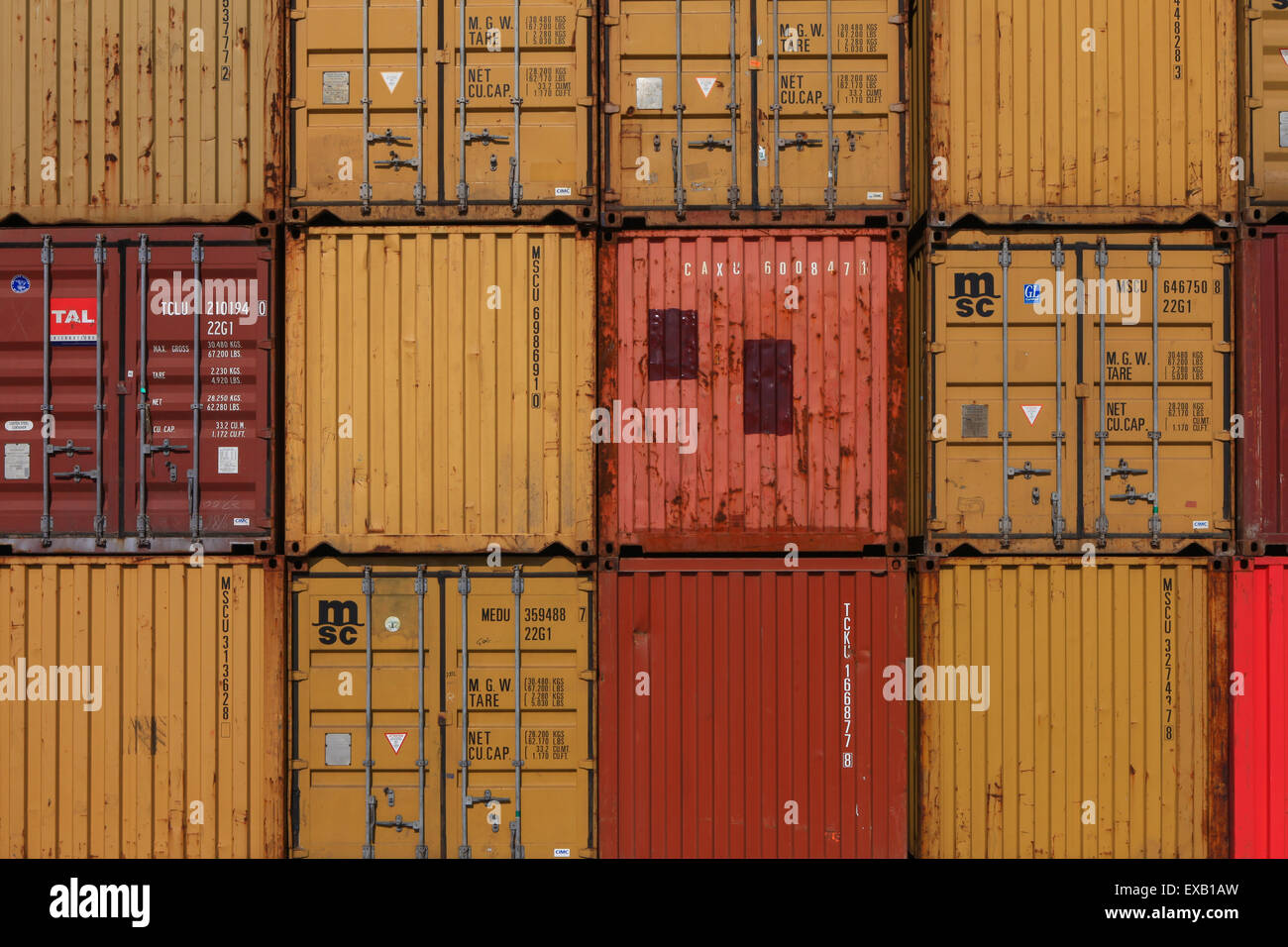 Various brands and colors of shipping containers stacked Stock Photo