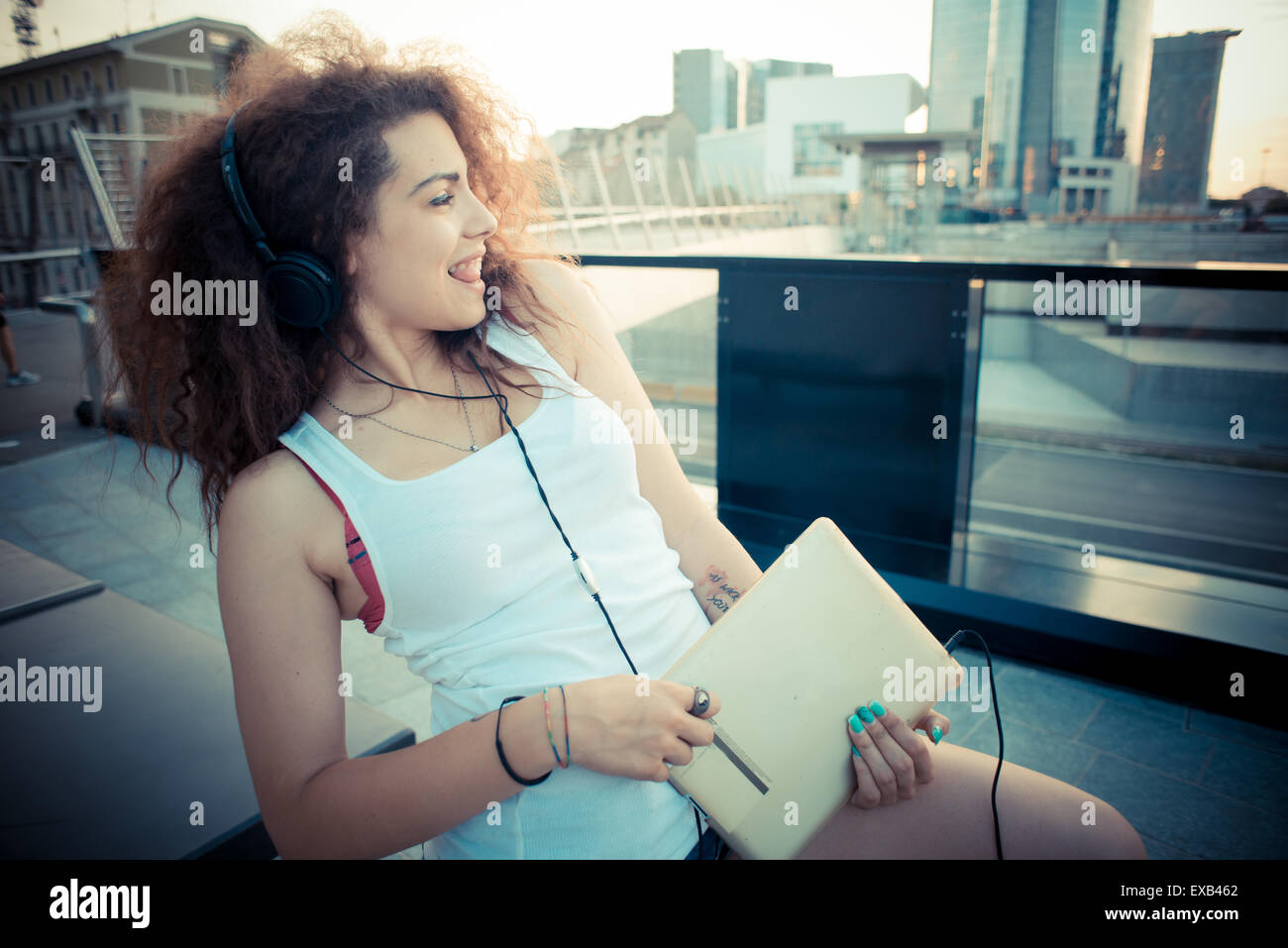 young beautiful long curly hair hipster woman listening to music with ...