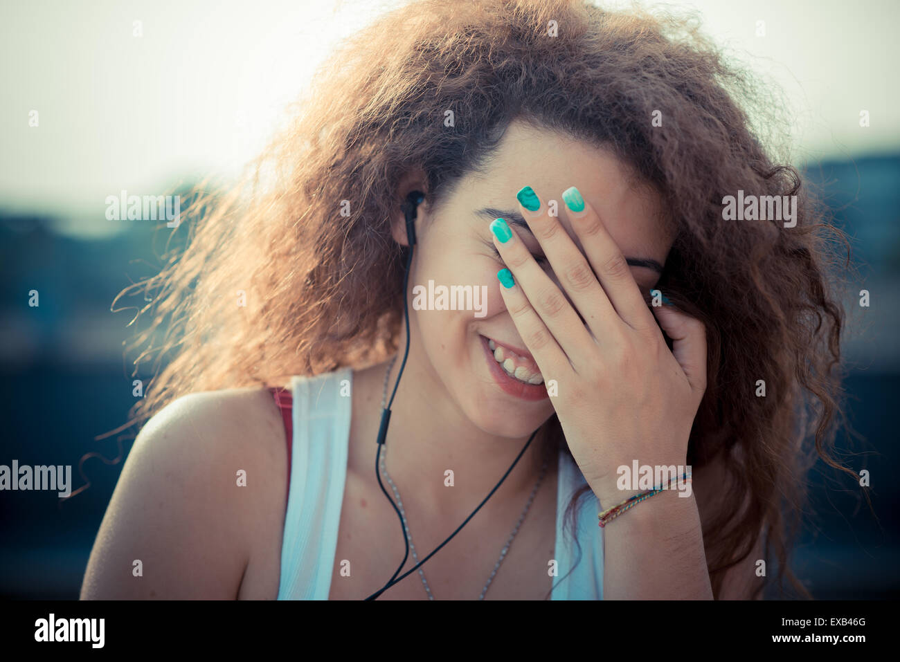 young beautiful long curly hair hipster woman listening to music with ...