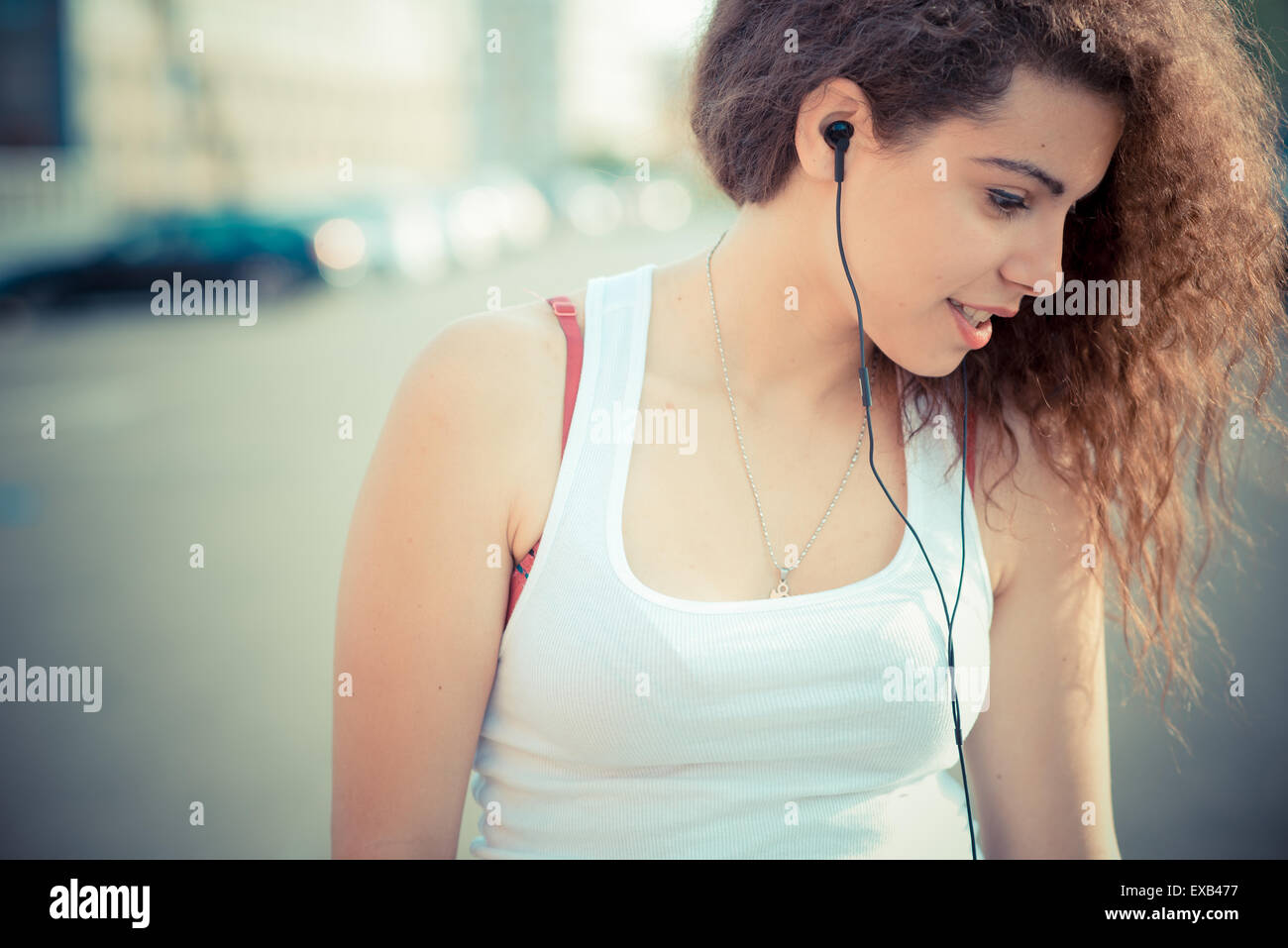 young beautiful long curly hair hipster woman listening to music with ...