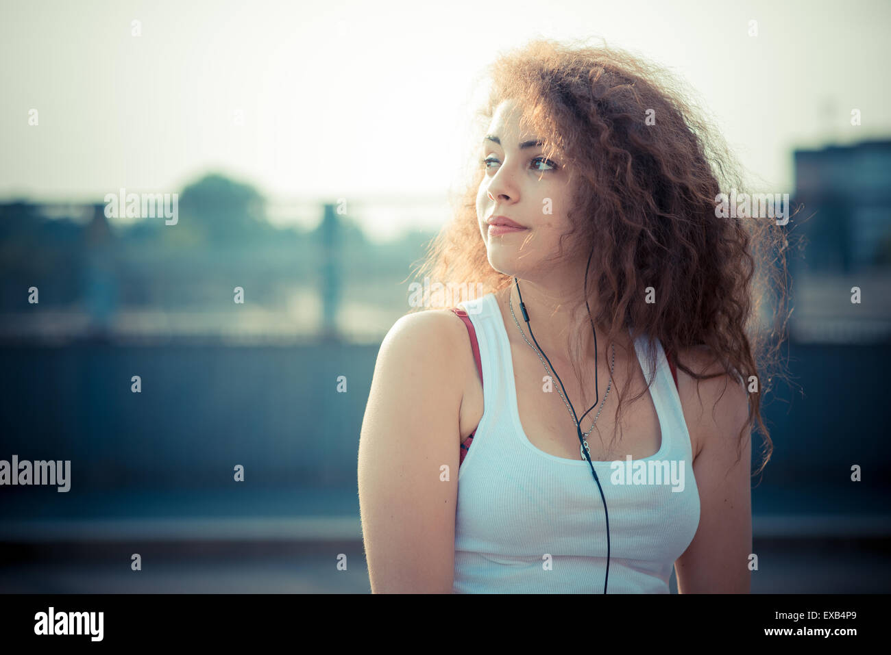 young beautiful long curly hair hipster woman listening to music with ...