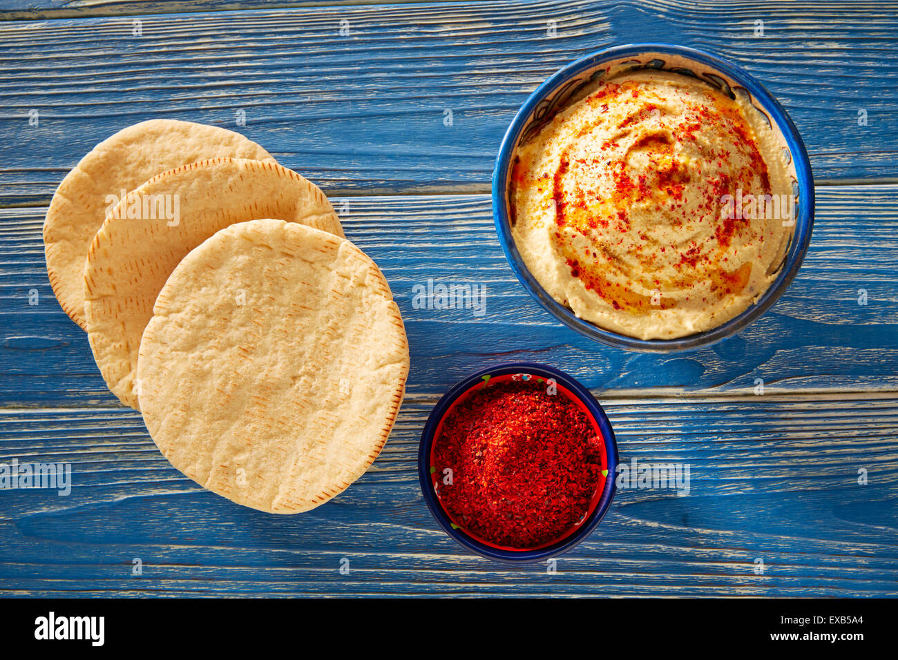 Hummus with pita bread and red pepper powder on blue Mediterranean wood ...