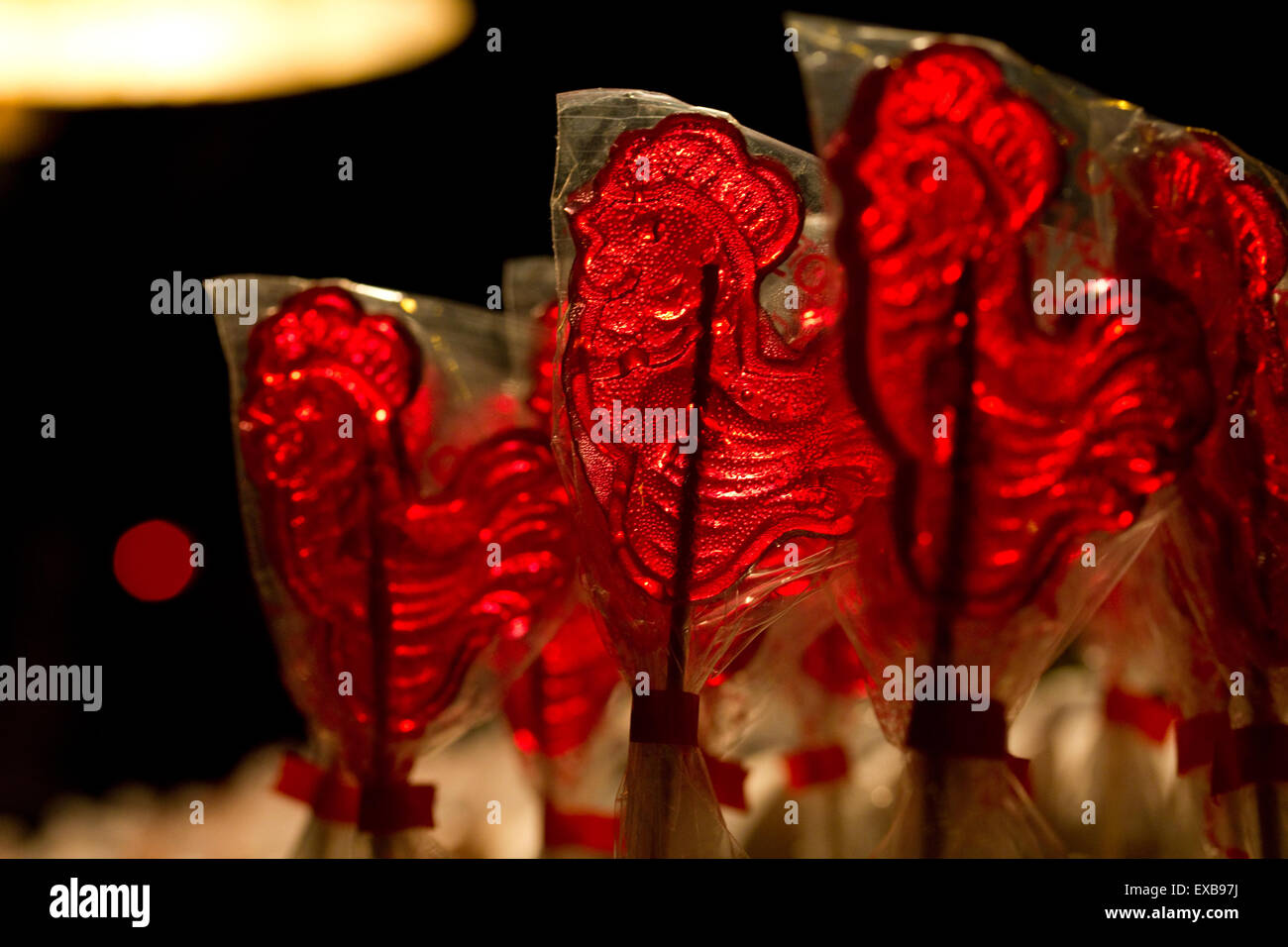 Backlit red rooster lollipops on a chapman's selling stand in central athens during the Greek antiausterity  protests. Stock Photo