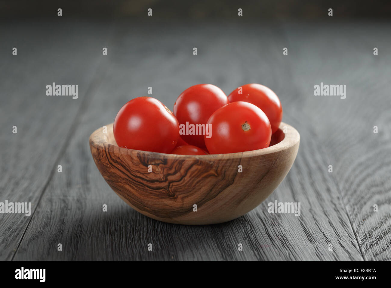 whole cherry tomatoes in olive dowl on wood table Stock Photo - Alamy