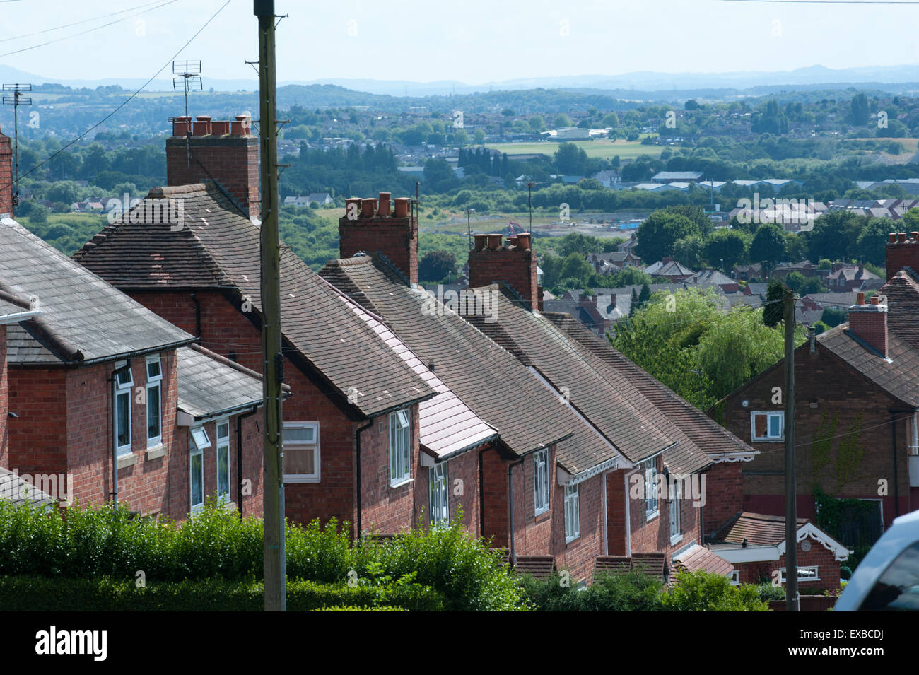View of roof tops and privet hedges in a traditional English council housing estate in Dudley with views out across countryside Stock Photo