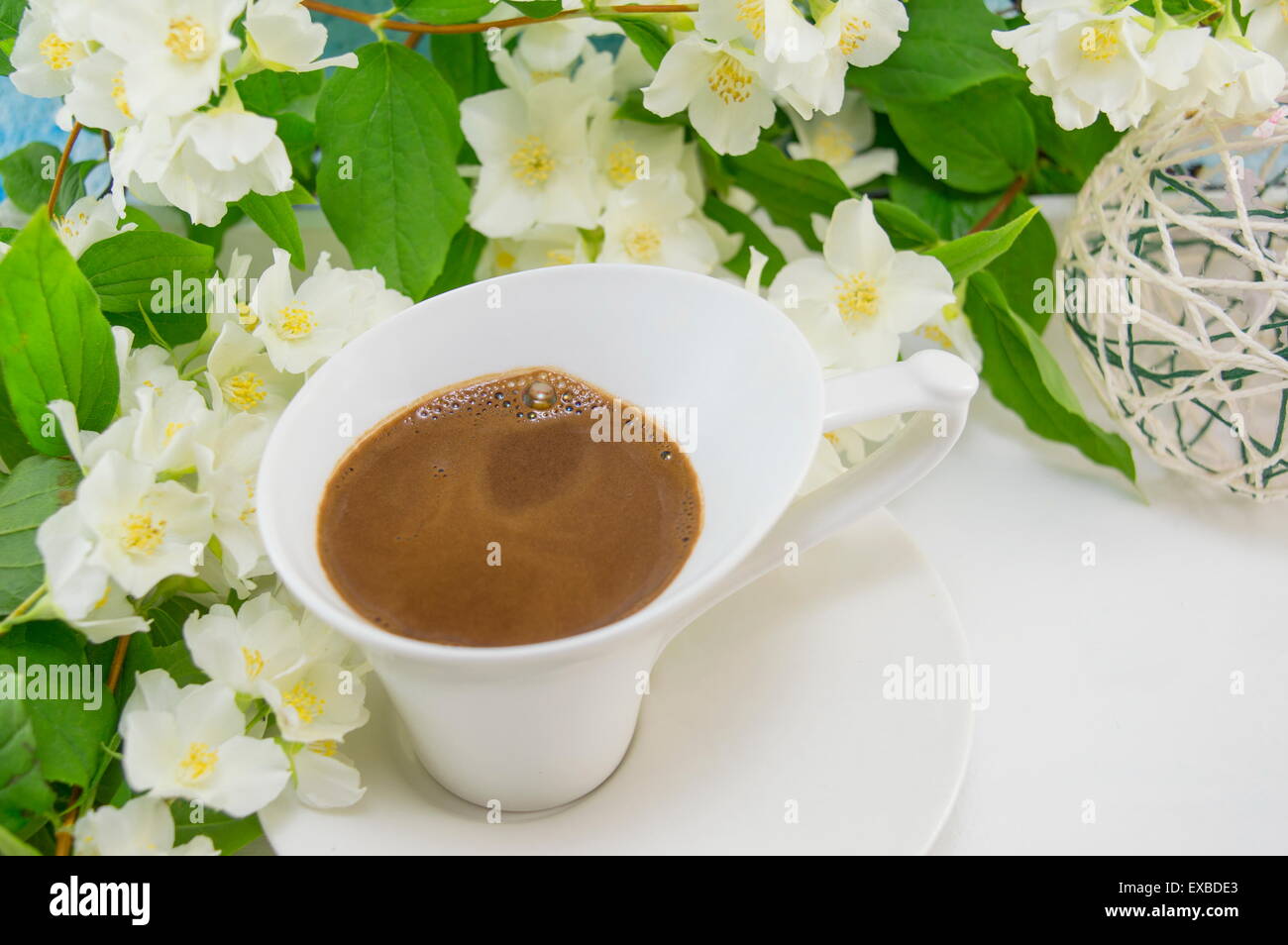 White cup of coffee on a wooden table decorated with flowers Stock Photo