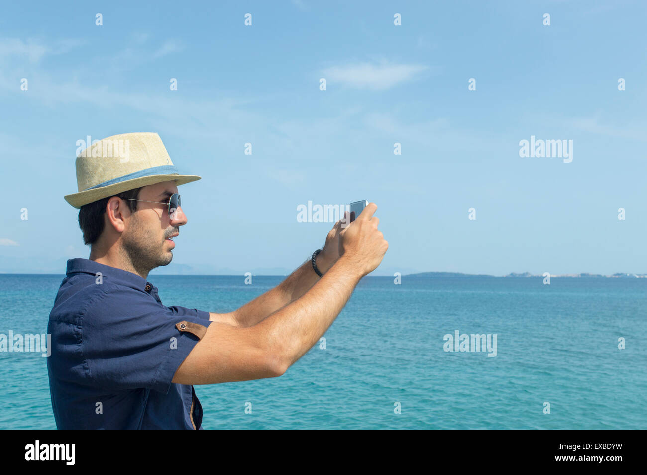 Man taking photos with his cell phone at the sea Stock Photo