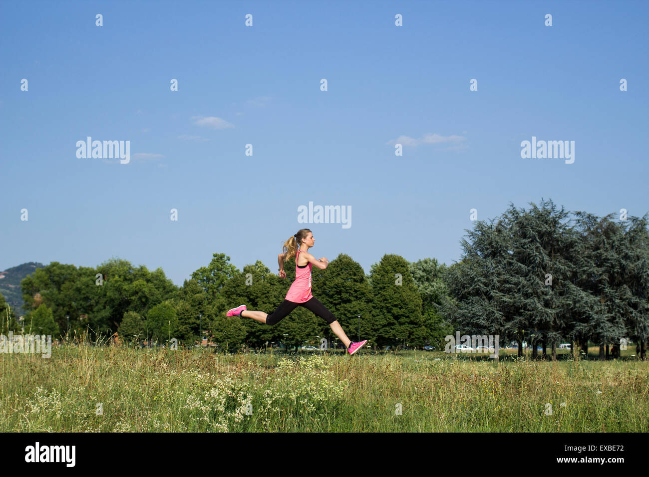 Blonde girl running at the park in the summer Stock Photo