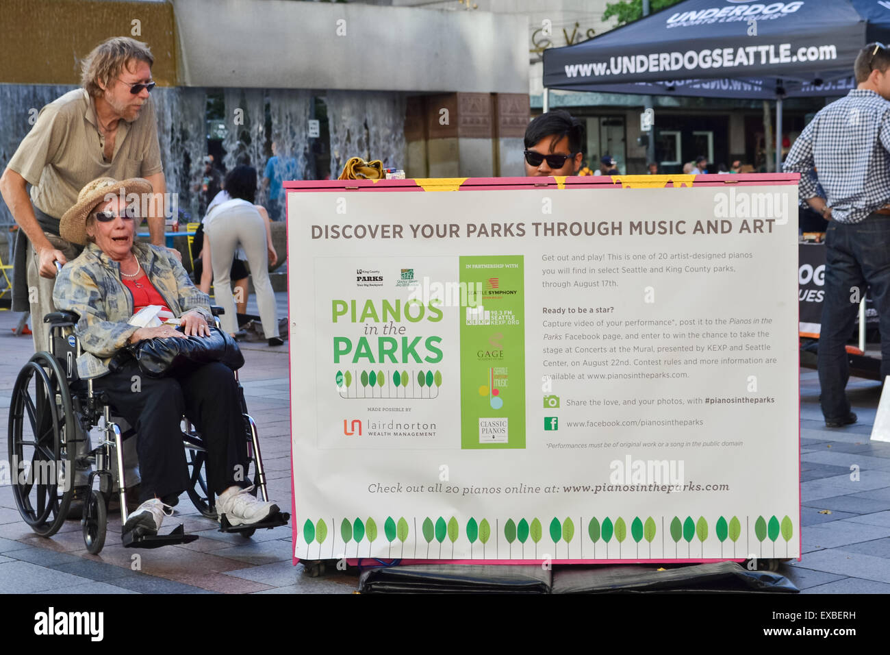 elderly woman in a wheelchair enjoying the piano in Westlake Park, Seattle, USA - park of Pianos in the Parks Stock Photo