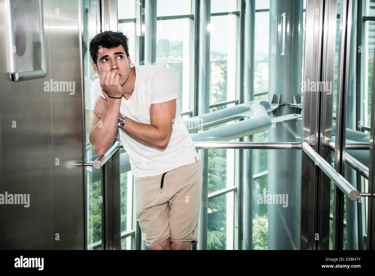 Scared young man desperate in stuck elevator screaming, looking very upset Stock Photo