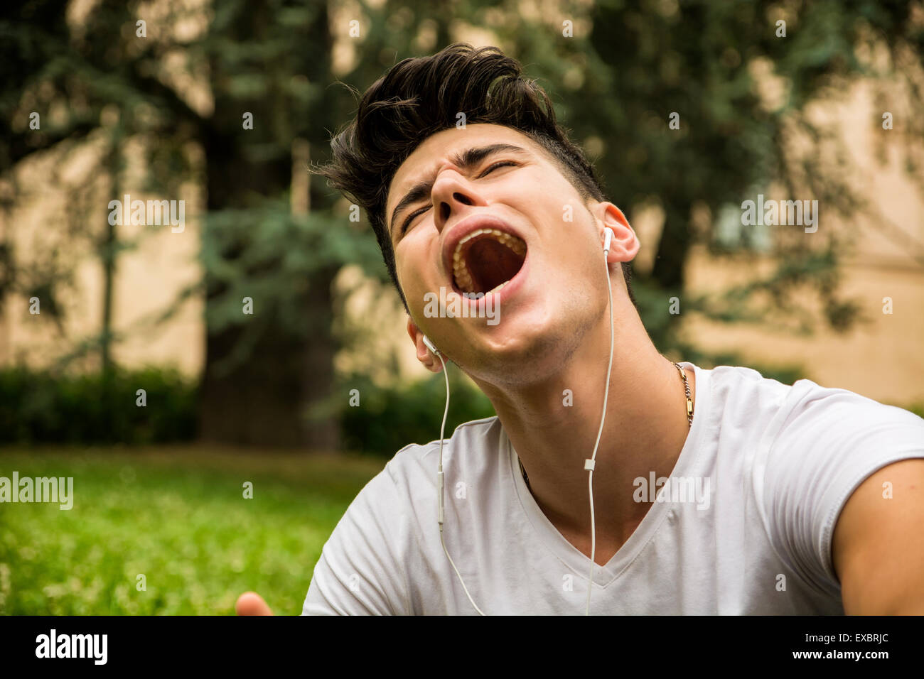 Close up Young Man Singing Out Loud While Listening to his Favorite Music Using Headphone at the Park. Stock Photo