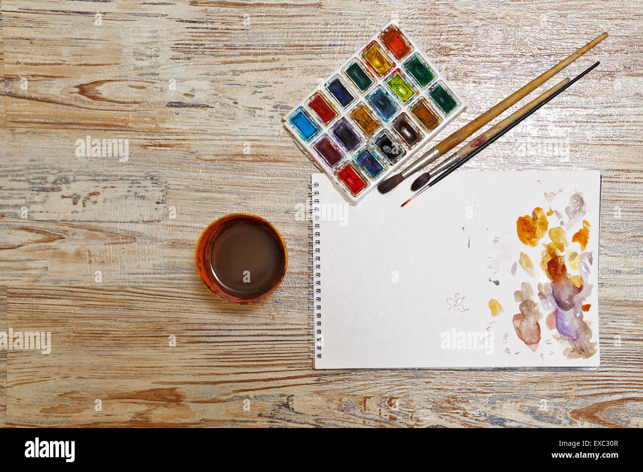 Watercolor paint, brushes and sketch pad on a wooden table. Watercolor  spots on the paper. Painter Tools group Stock Photo - Alamy