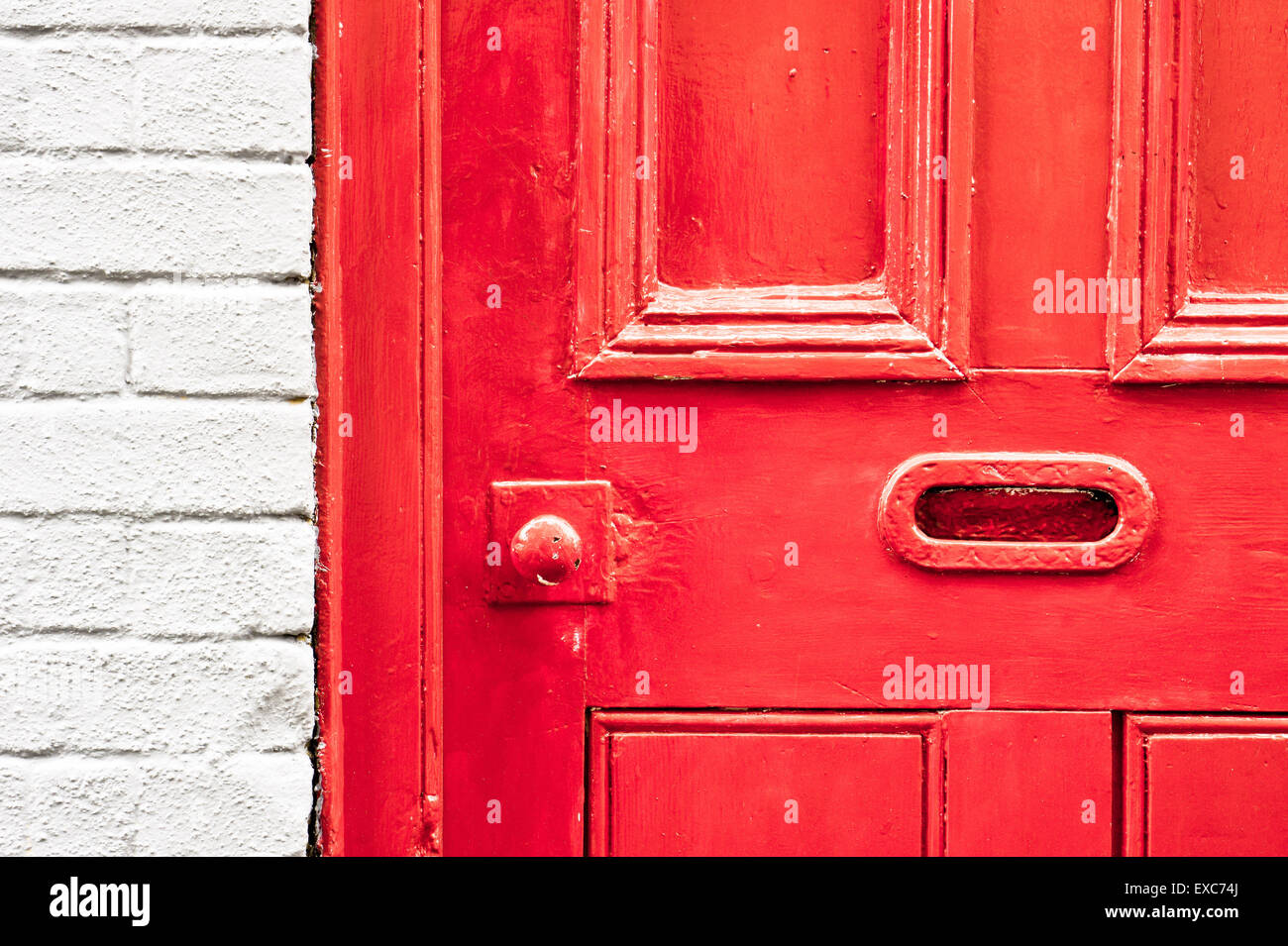 A vibrant red painted wooden front door with a letterbox Stock Photo