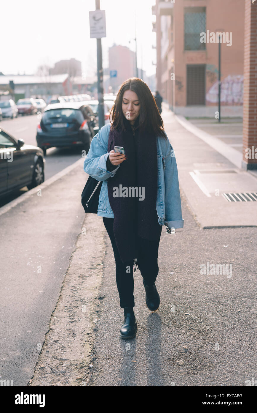 Young beautiful brunette caucasian girl walking down the street while ...
