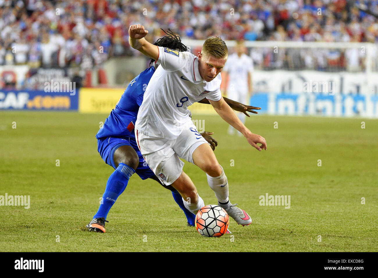 Foxborough, Massachusetts, USA. 10th July, 2015. United States forward Aron Johannsson (9) keeps the ball from Haiti defender Reginald Goreux (8) during the CONCACAF Gold Cup group stage match between USA and Haiti held at Gillette Stadium, in Foxborough Massachusetts. USA defeated Haiti 1-0. Eric Canha/CSM/Alamy Live News Stock Photo