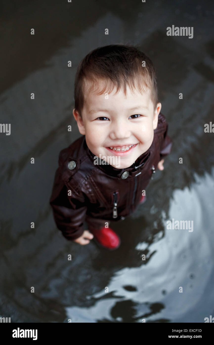 Boy in rubber boots plays at a puddle Stock Photo Alamy