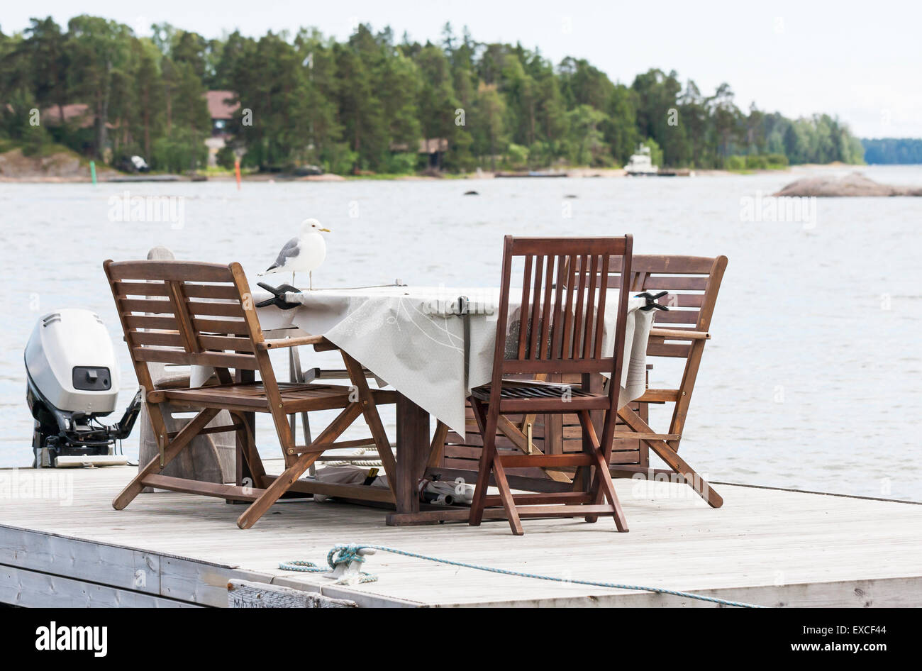 Big white seagull or mew stand on a garden table which is placed on a floating base. Stock Photo