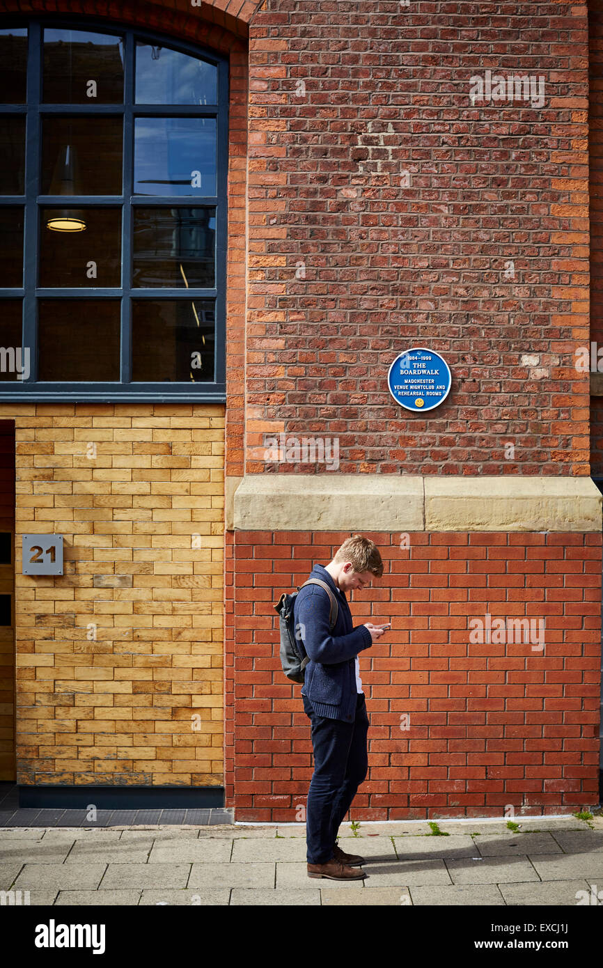 The old Boardwalk nightclub in Manchester UK a man passes stops to text from mobile phone cellphone looking at screen texting sm Stock Photo