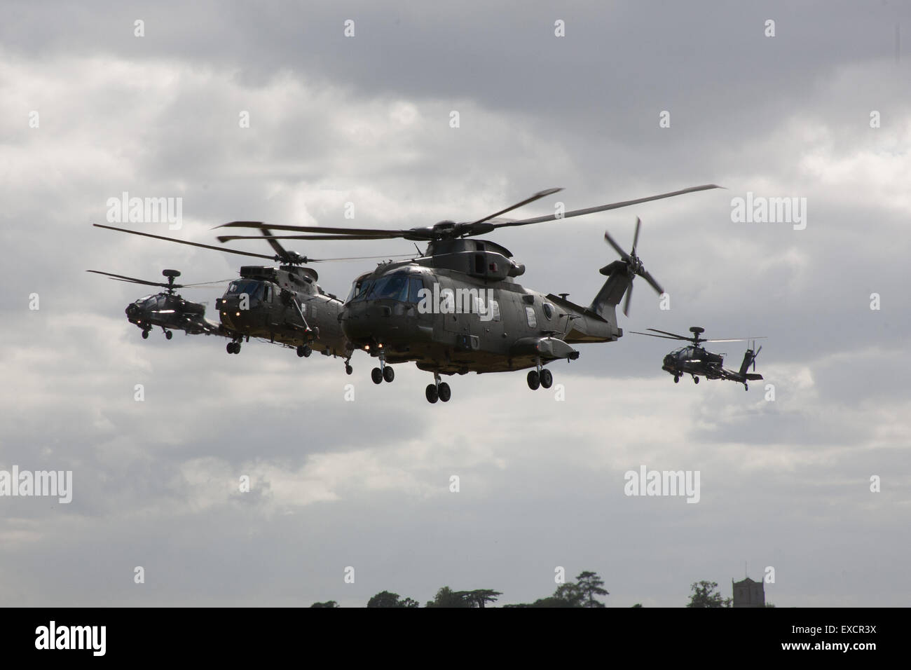 Yeovilton, Somerset, UK. 11th July, 2015. One of the Fleet Air Arms new Merlin H C mk 3 leads a Sea King H C mk 4 during flying at Yeovilton International Air Day, flanked by a pair of Apache Attack Helicopters flown by the Army AIr Corps, The Merlin will have fully replaced the Sea King in the Commando Helicopter Force by March 2016 Credit:  David Billinge/Alamy Live News Stock Photo