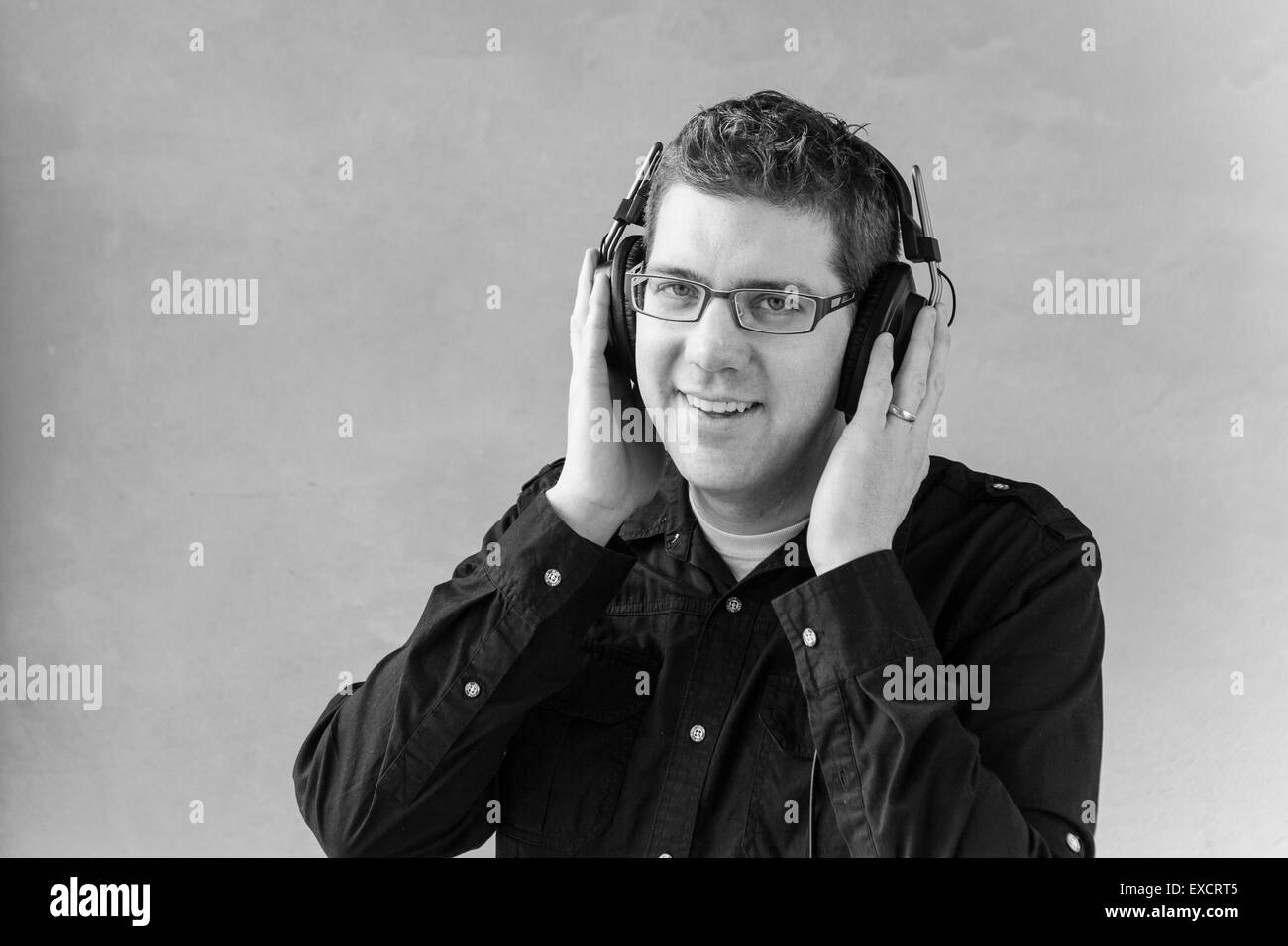 a black and white studio portrait of a stylish hipster DJ wearing his headphones Stock Photo