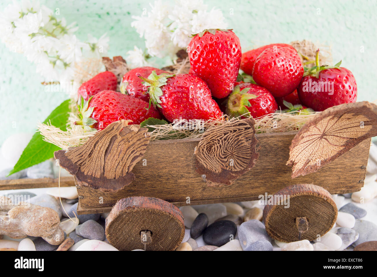 Bunch of fresh strawberries stacked on miniature old carts Stock Photo