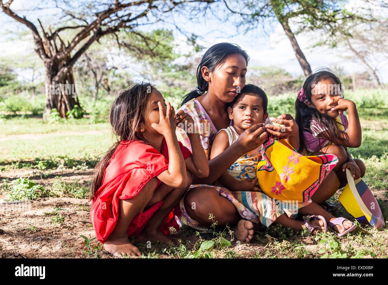 Young Wayuu woman and her children sitting outside while she knits in a 'rancheria', or traditional Wayuu settlement in La Guaji Stock Photo