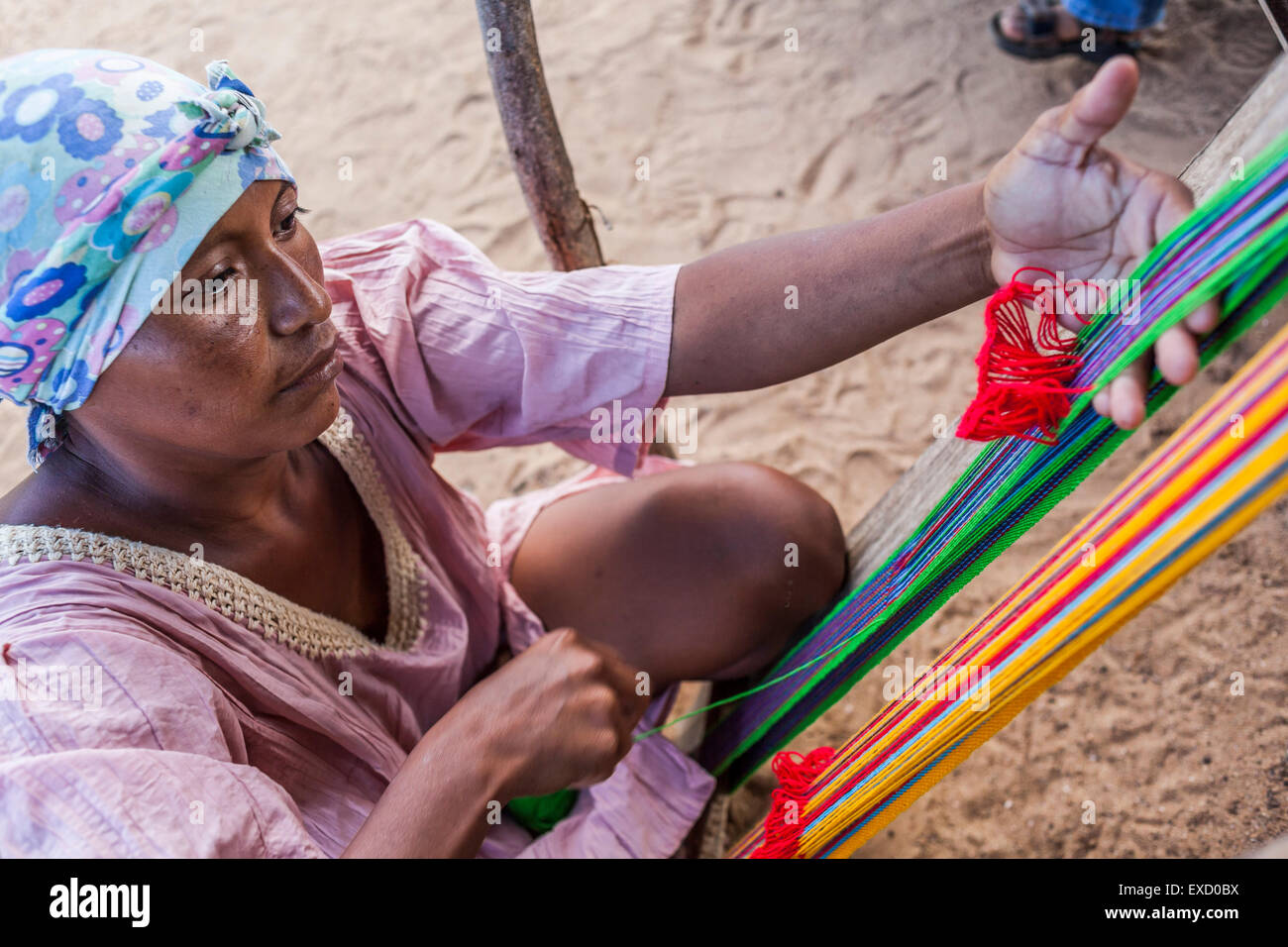 Young Wayuu indigenous woman in a Wayuu 'rancheria', or rural village, weaving textiles on a loom, Uribia, La Guajira, Colombia. Stock Photo