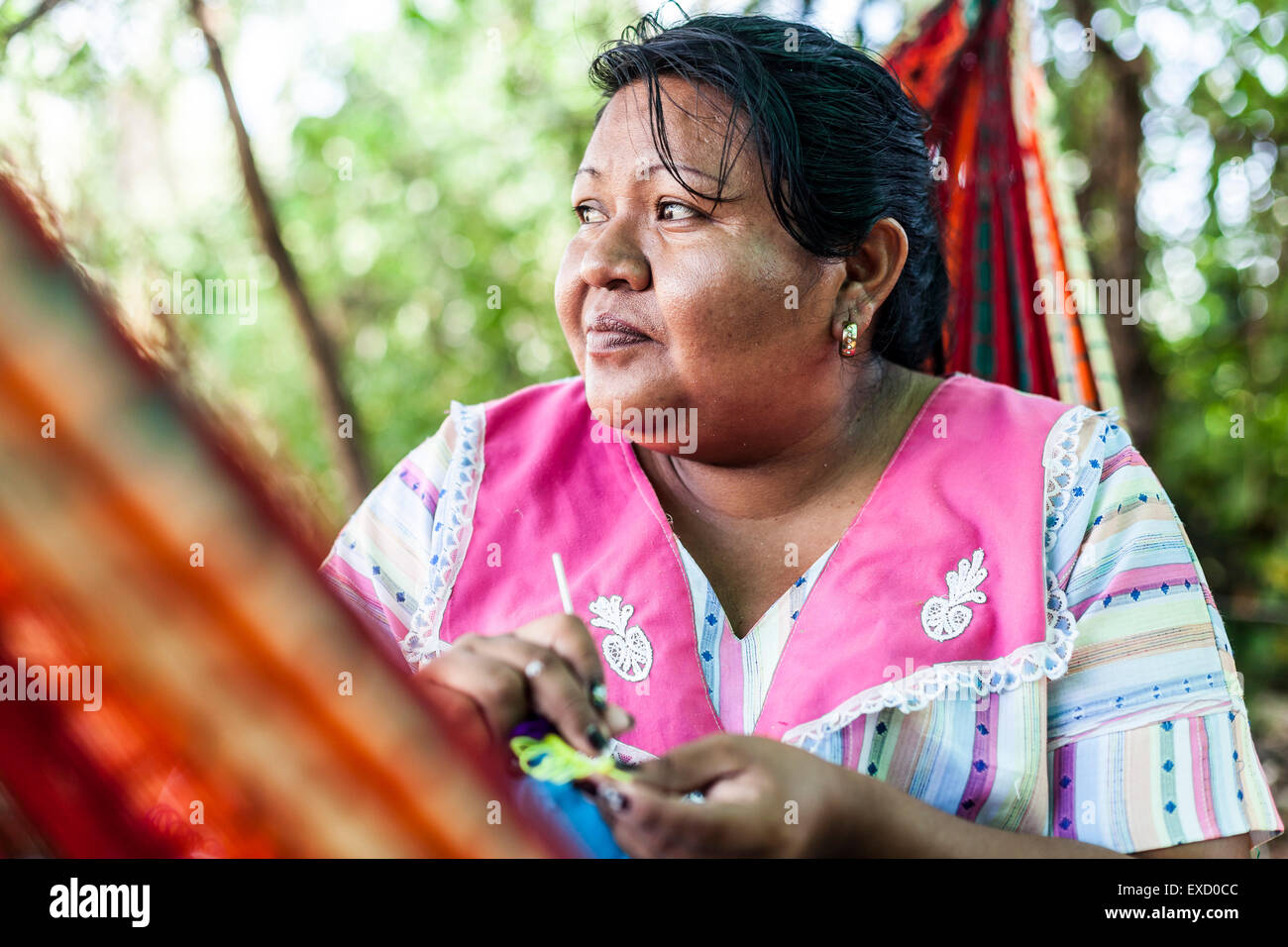 Middle-aged Wayuu indigenous woman knitting in a 'chinchorro' or Colombian hammock.   Knitting, crocheting and weaving are funda Stock Photo