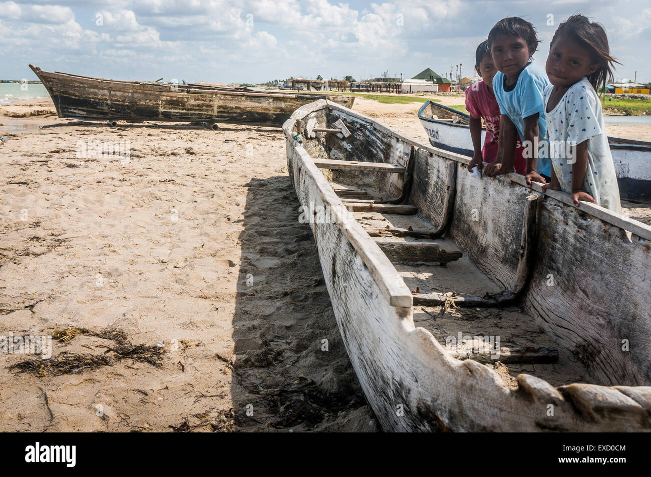 Children posing with an old dugout canoe and fishing boat on the beach at Manaure, La Guajira, Colombia. Stock Photo