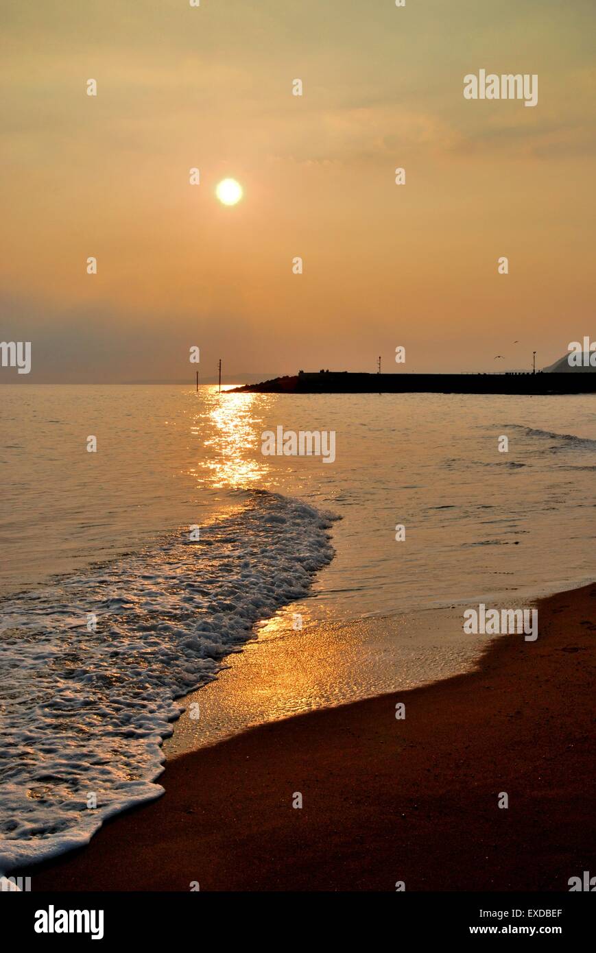 Sunset over soft gentle waves on a beach, Serene coastal scene. Stock Photo