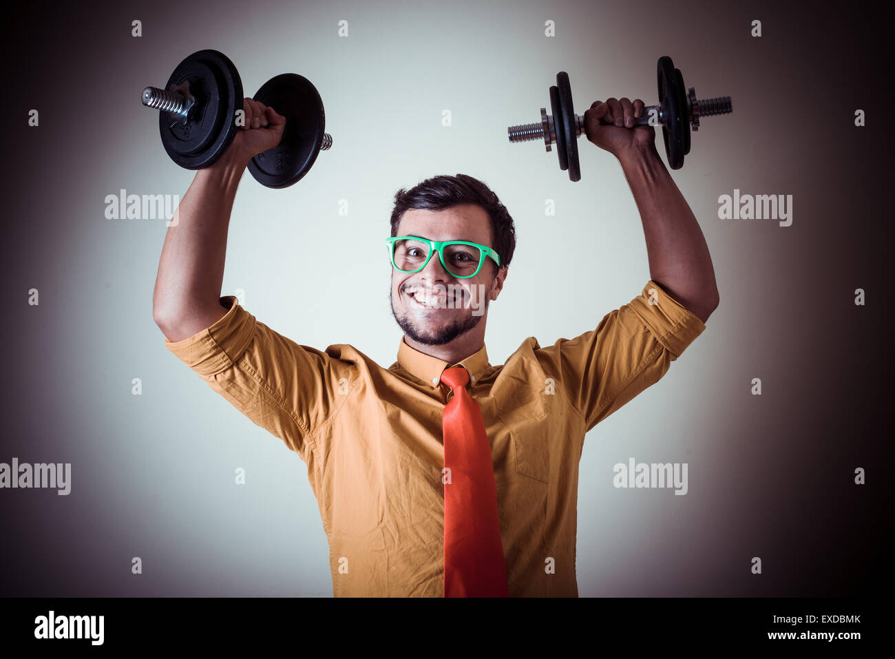 funny crazy young man weightlifting on gray background Stock Photo