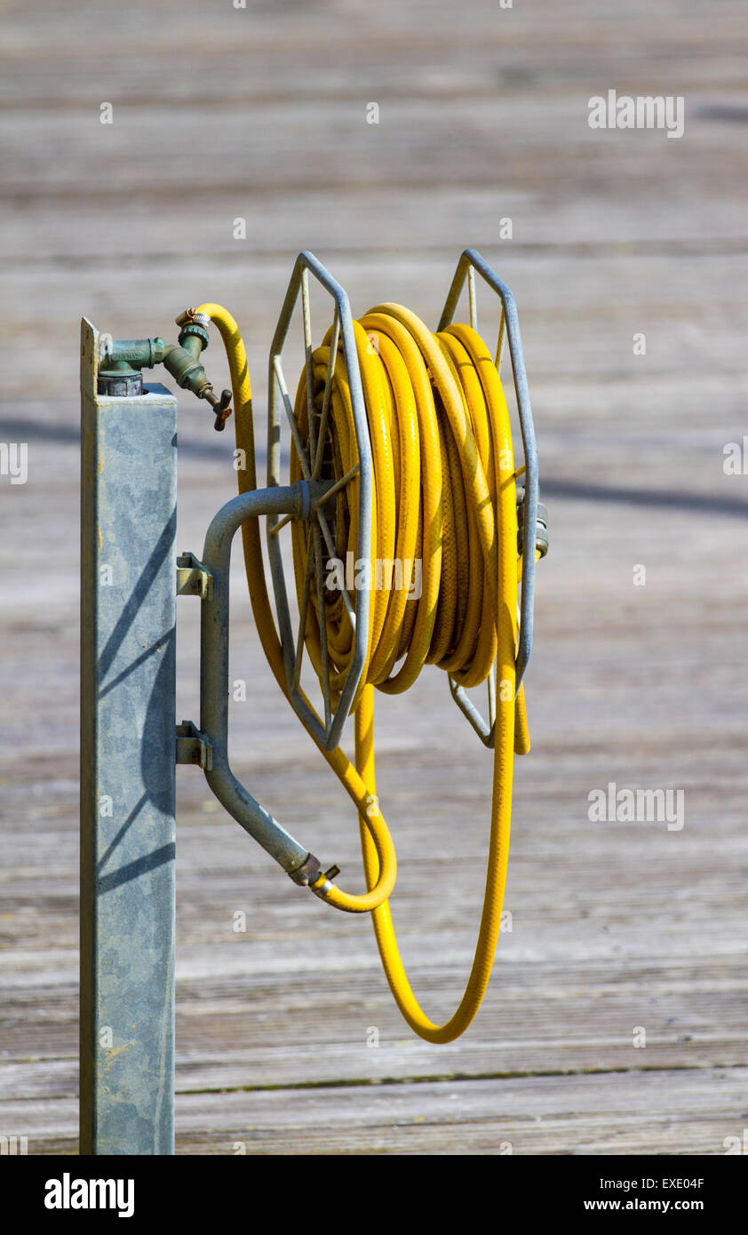 Rolled up hose reel on a wooden quayside Stock Photo