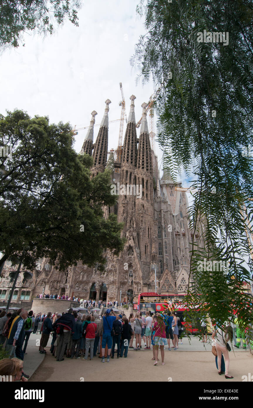 Tourists looking at the Nativity Facade of the La Sagrada Familia from Placa de Gaudi gardens Stock Photo