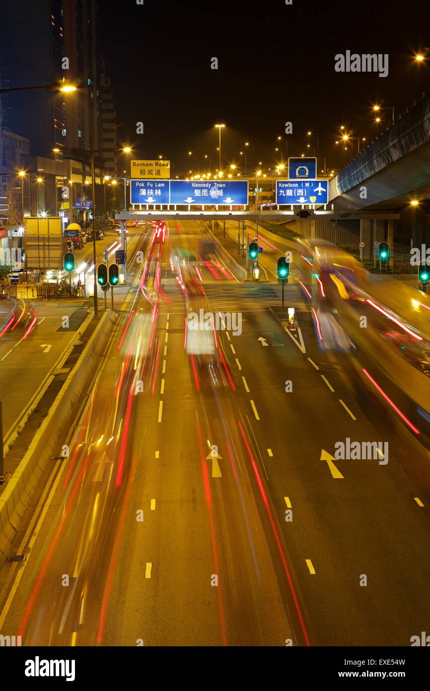 Night shot of busy road in Hong Kong central. Traffic pulling away from green lights giving an effective motion blur. Stock Photo