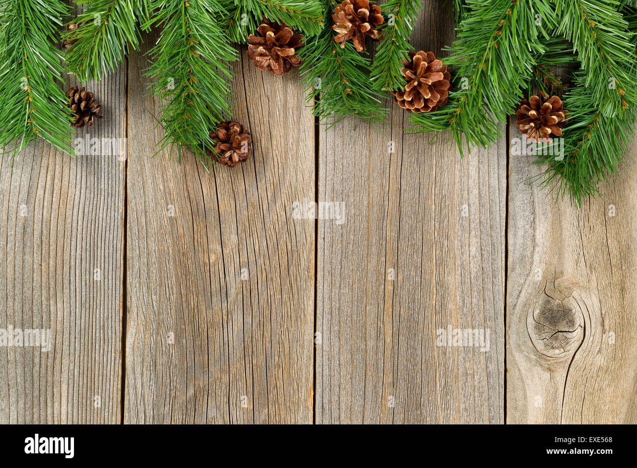 Christmas border with pine tree branches and cones on rustic wooden boards. Stock Photo