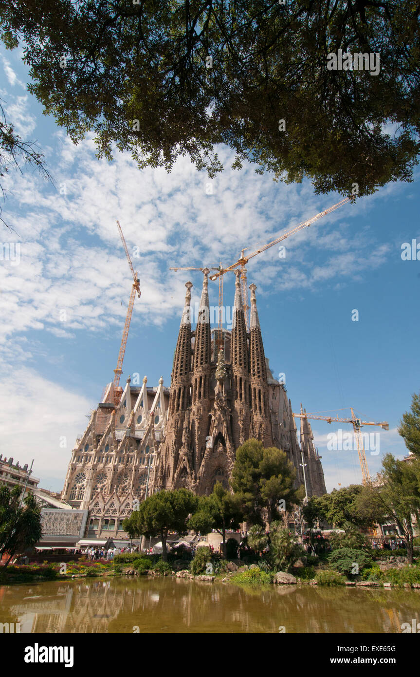 Looking across Placa de Gaudi gardens lake towards La Sagrada Familia Stock Photo