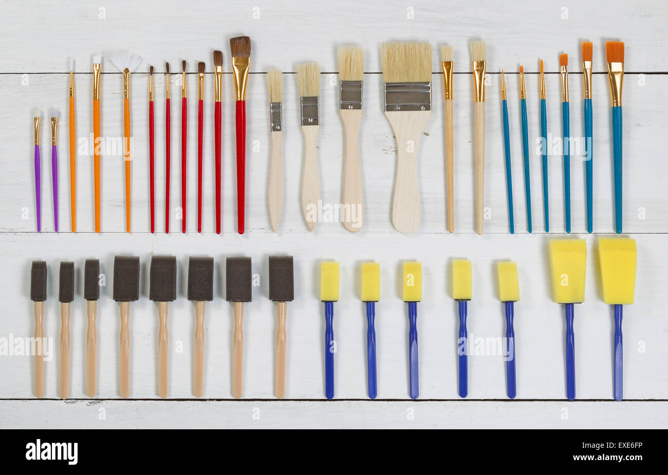 High angled view of brand new paint brushes and applicators organized on white wood. Layout in horizontal format. Stock Photo