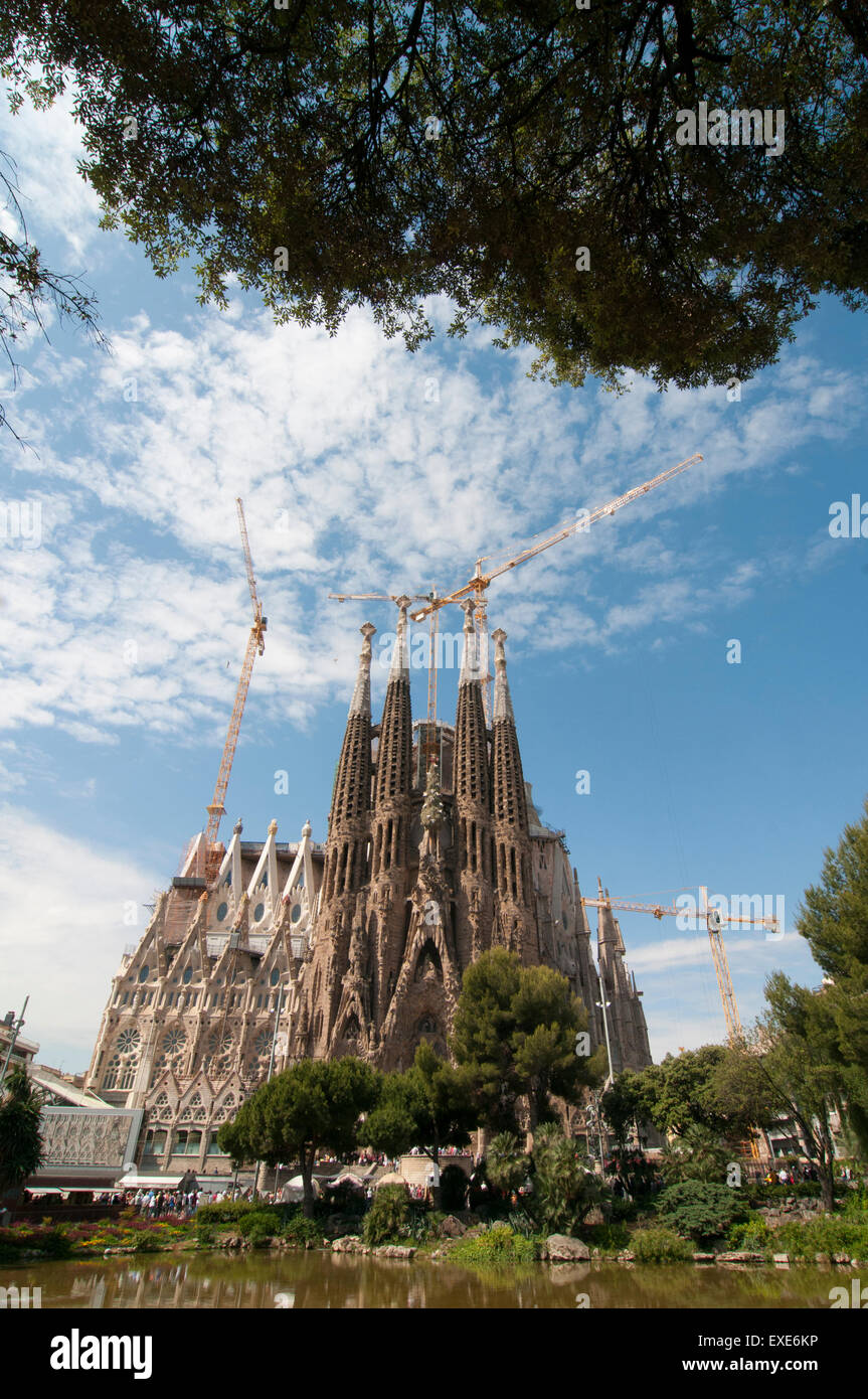 Looking across Placa de Gaudi gardens lake towards La Sagrada Familia Stock Photo