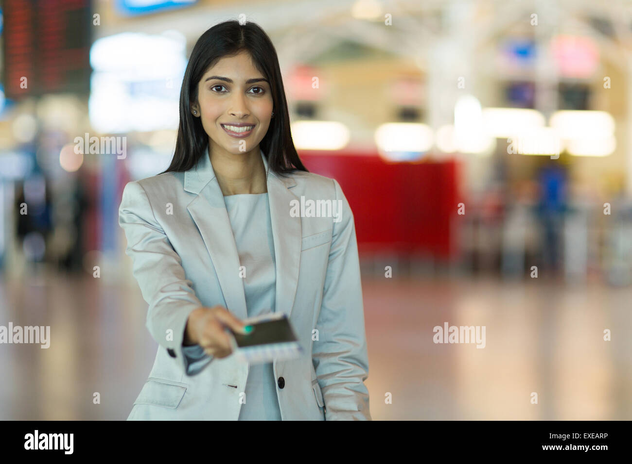 happy Indian woman handing over air ticket at airline check in counter Stock Photo