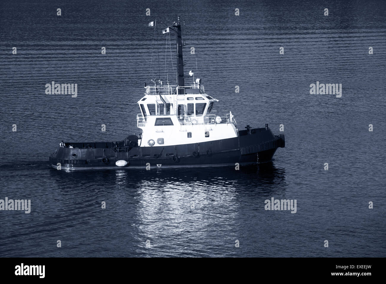Tug boat with white superstructure underway, side view, monochrome photo Stock Photo