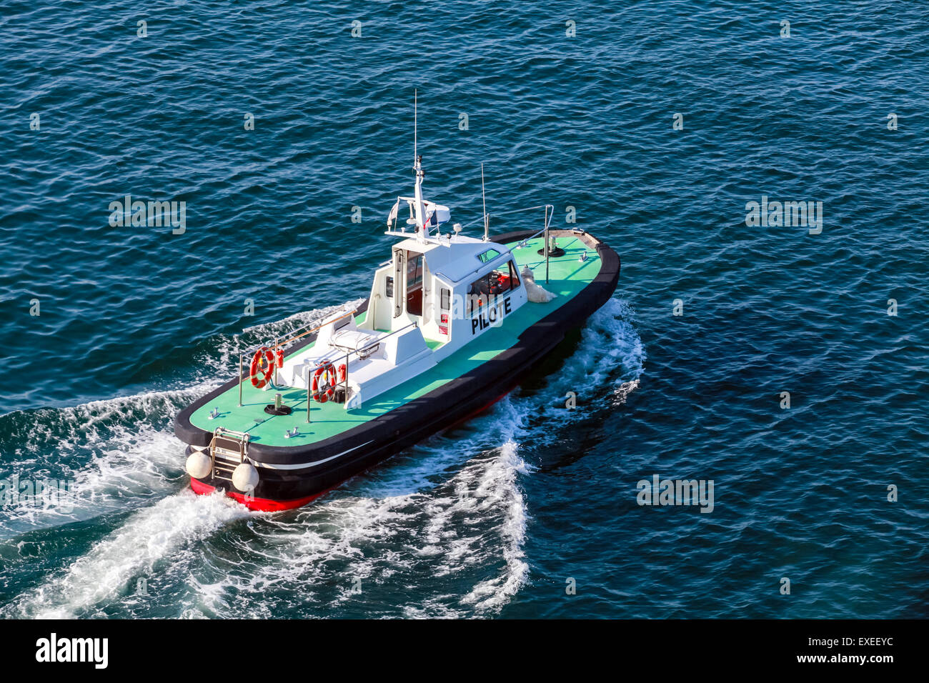 Small pilot boat with green deck and black hull is underway on a sea water Stock Photo