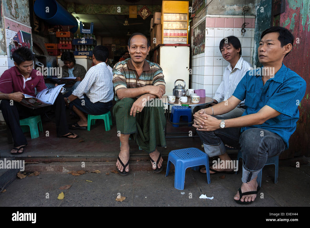 Local men drinking coffee in front of a small cafe, Yangon, Myanmar Stock Photo