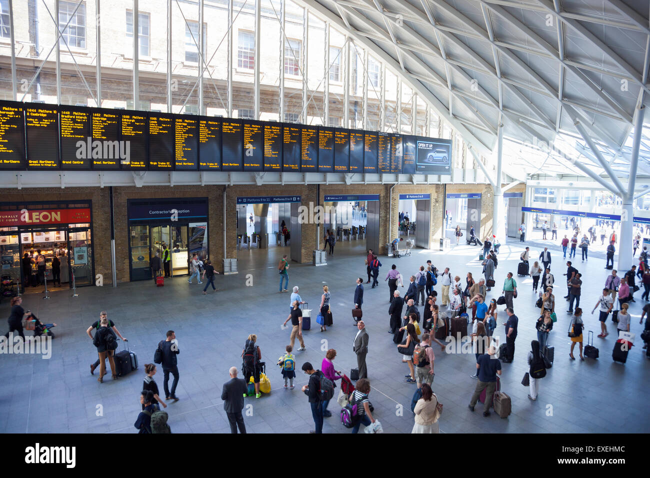 Commuters looking at the departures board at King's Cross rail station London, England Stock