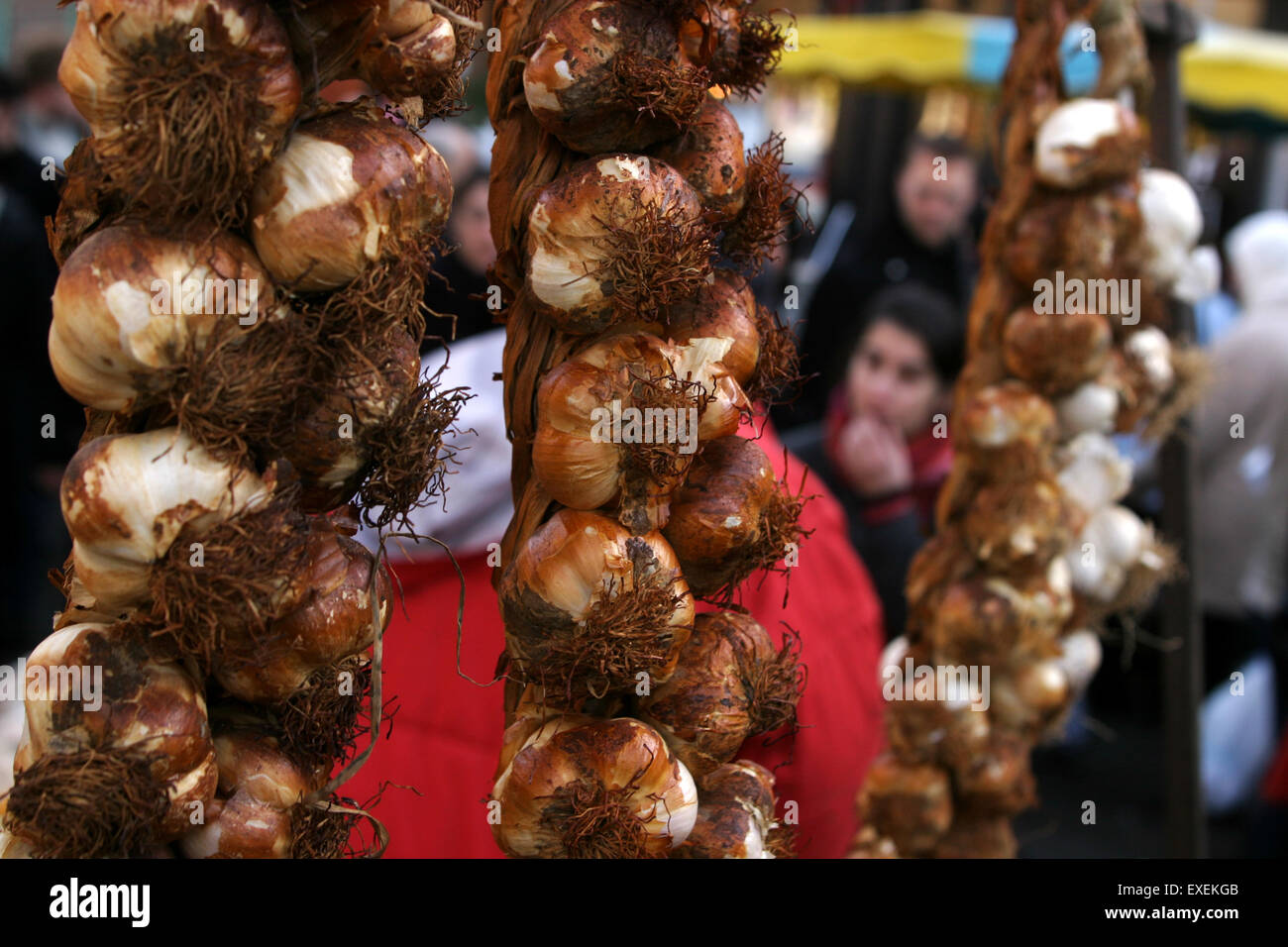 A roasted garlic display hanging on a market stall in Lille, France. Stock Photo